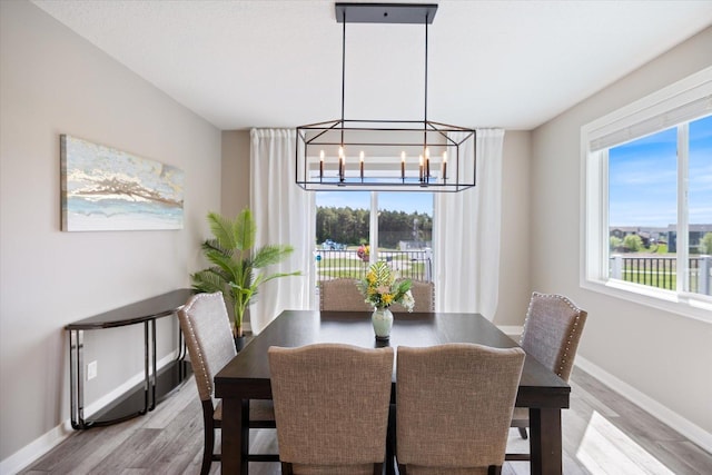 5360 Pine Island Rd, Woodbury, MN 55129 - dining space featuring light wood-style flooring, baseboards, and a chandelier