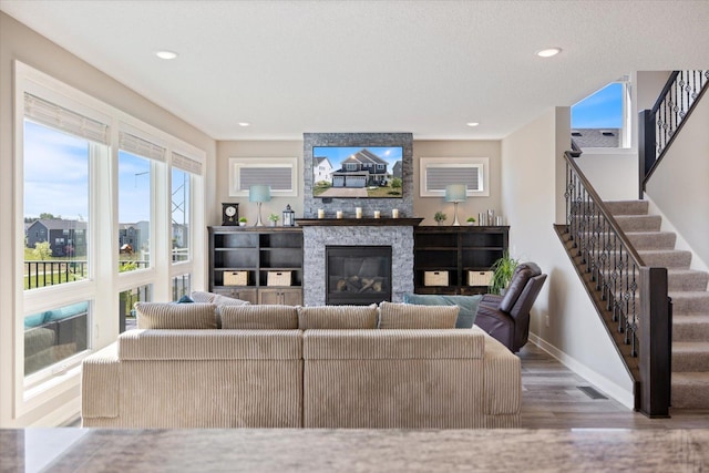 5360 Pine Island Rd, Woodbury, MN 55129 - living room with wood finished floors, a stone fireplace, baseboards, stairway, and recessed lighting