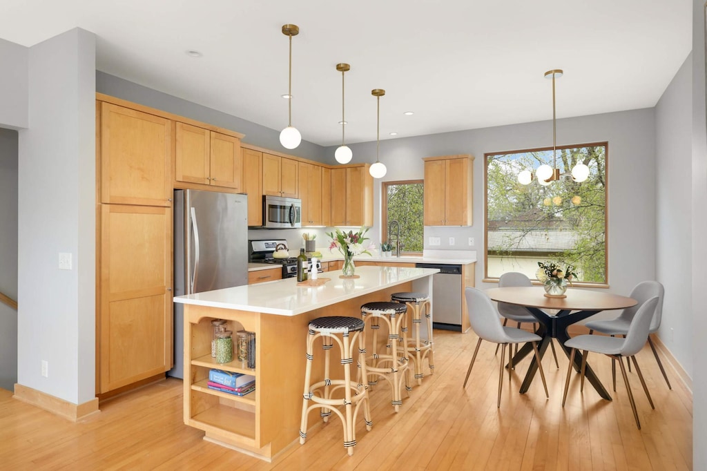 6839 Penn Ave S, Richfield, MN 55423 - kitchen with appliances with stainless steel finishes, light countertops, light wood-type flooring, a kitchen island, and open shelves