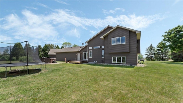 28306 State Highway 25, Belle Plaine, MN 56011 - rear view of house featuring a trampoline, a lawn, a hot tub, and a wooden deck