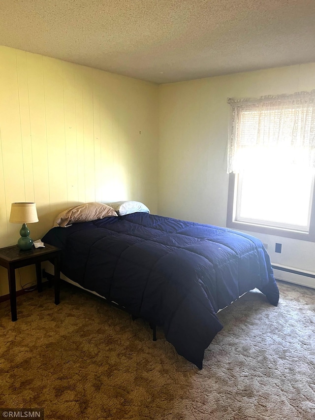 bedroom with carpet floors, a baseboard heating unit, and a textured ceiling