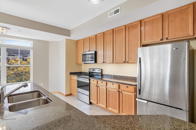 kitchen with dark stone countertops, light tile patterned floors, visible vents, appliances with stainless steel finishes, and a sink
