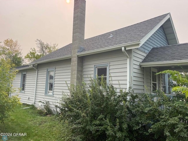view of property exterior featuring a chimney and a shingled roof