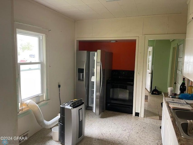 kitchen featuring black electric range, a sink, stainless steel refrigerator with ice dispenser, and a wealth of natural light