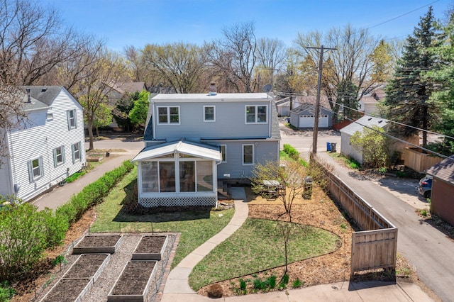 back of property featuring a sunroom, a lawn, a vegetable garden, and fence private yard