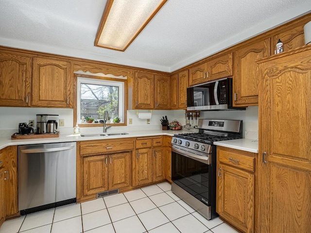 kitchen featuring appliances with stainless steel finishes, brown cabinetry, and a sink