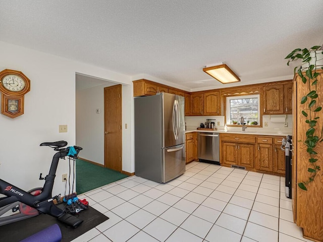 kitchen with stainless steel appliances, brown cabinetry, visible vents, a sink, and light countertops