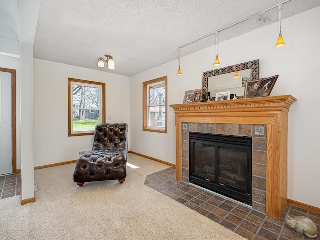 sitting room with a textured ceiling, carpet, baseboards, and a tiled fireplace