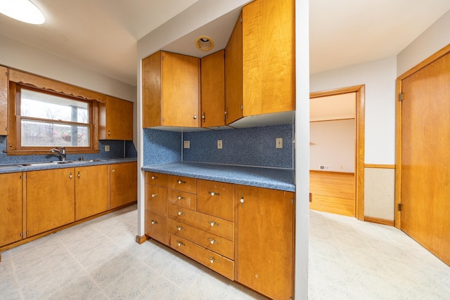 kitchen featuring brown cabinets, tasteful backsplash, and a sink
