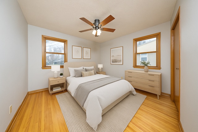 bedroom featuring light wood finished floors, baseboards, and ceiling fan