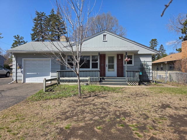 view of front facade featuring a chimney, fence, driveway, covered porch, and a garage