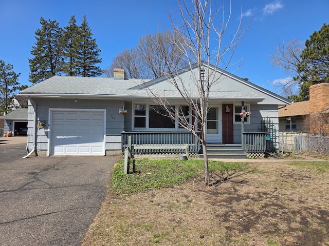 view of front facade with a porch, a chimney, fence, an attached garage, and aphalt driveway