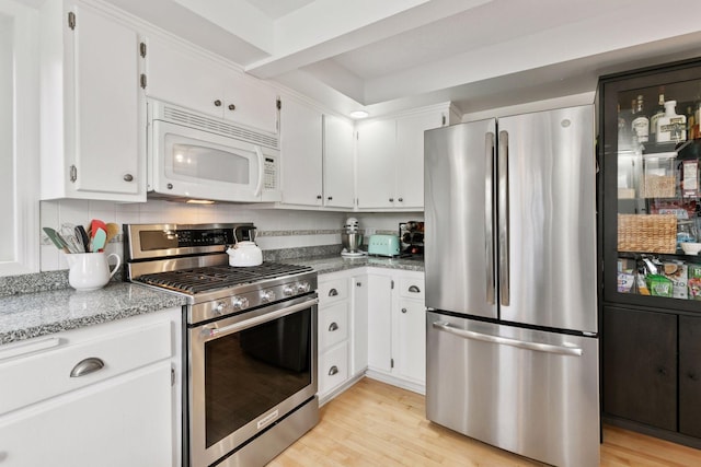 kitchen featuring light stone countertops, stainless steel appliances, white cabinets, and light wood-style flooring