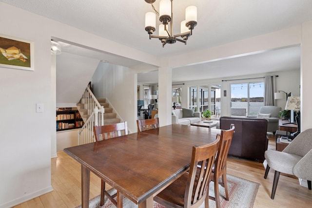 dining space featuring stairway, an inviting chandelier, and light wood-style floors