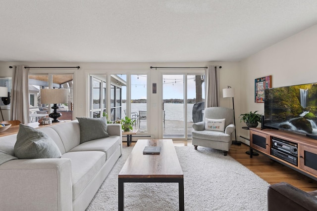 living area with wood finished floors, a baseboard heating unit, a textured ceiling, and a baseboard radiator