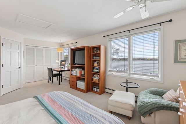 bedroom with attic access, a closet, a baseboard heating unit, and light carpet