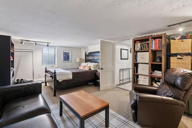 bedroom with a textured ceiling, rail lighting, and light carpet