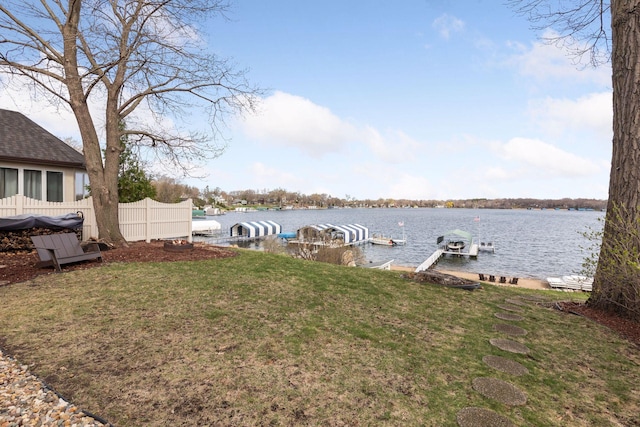 dock area featuring fence, a yard, a water view, and boat lift
