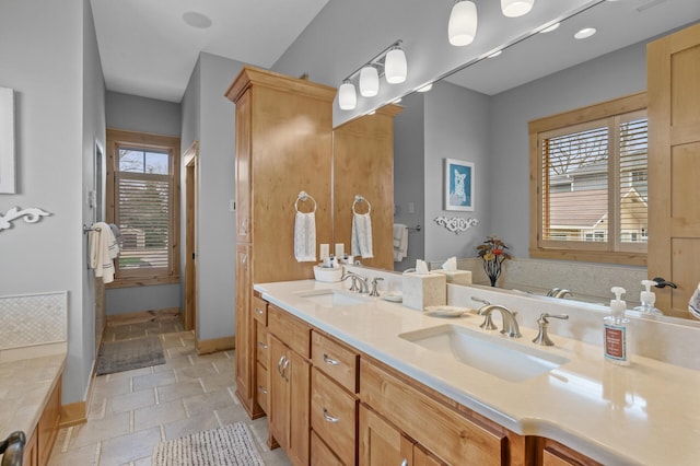 623 Shore Dr, Forest Lake, MN 55025 - bathroom featuring a sink, baseboards, double vanity, and stone tile flooring