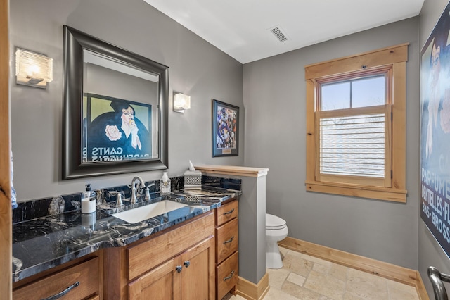 623 Shore Dr, Forest Lake, MN 55025 - bathroom featuring vanity, toilet, baseboards, visible vents, and stone tile flooring