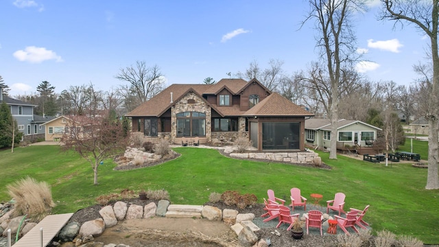 623 Shore Dr, Forest Lake, MN 55025 - back of house with a lawn, stone siding, a fire pit, and a sunroom