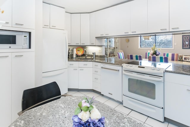 10411 Cedar Lake Rd Unit 301, Minnetonka, MN 55305 - kitchen with dark stone countertops, light tile patterned floors, white cabinets, a sink, and white appliances