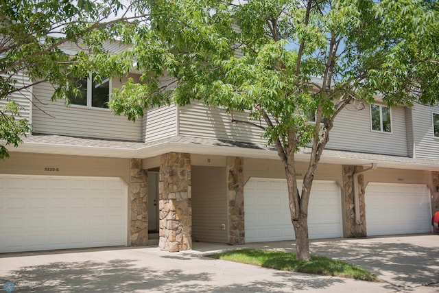 3220 40th Ave S Unit D, Fargo, ND 58104 - view of front of home with a garage, driveway, stone siding, and a shingled roof