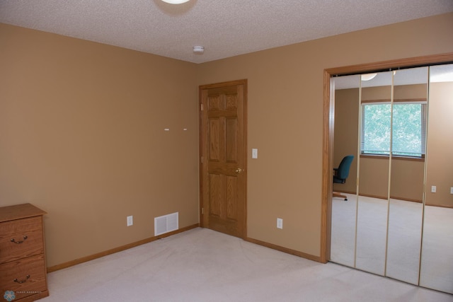 3220 40th Ave S Unit D, Fargo, ND 58104 - unfurnished bedroom featuring a closet, baseboards, visible vents, a textured ceiling, and light carpet