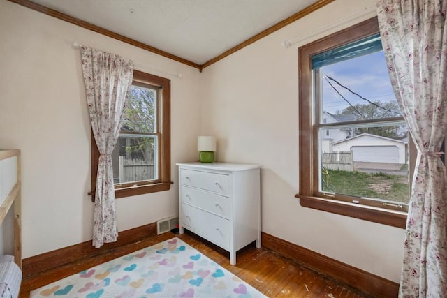 bedroom with visible vents, wood finished floors, baseboards, and ornamental molding