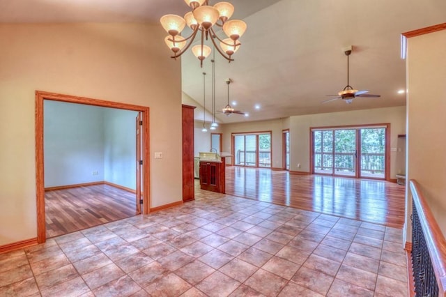 spare room with baseboards, light wood-type flooring, ceiling fan with notable chandelier, and high vaulted ceiling