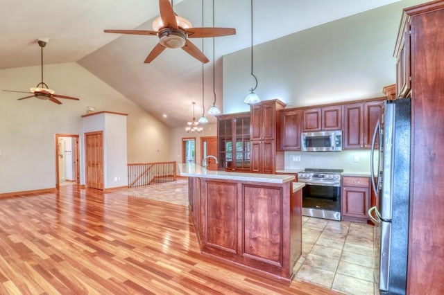 kitchen with ceiling fan with notable chandelier, open floor plan, high vaulted ceiling, light countertops, and appliances with stainless steel finishes