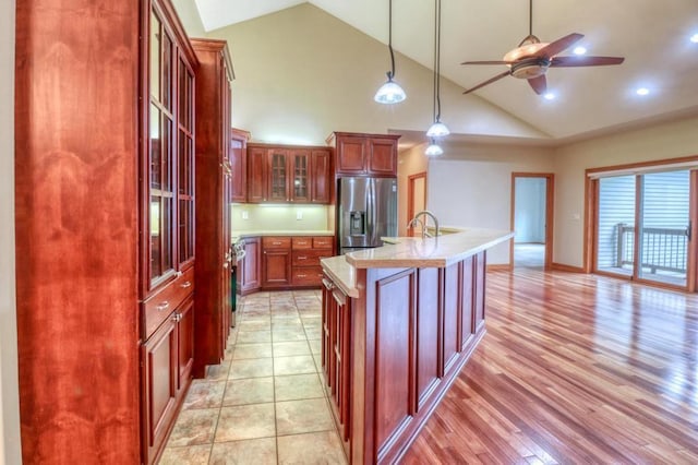kitchen with ceiling fan, dark brown cabinets, light countertops, stainless steel fridge with ice dispenser, and glass insert cabinets