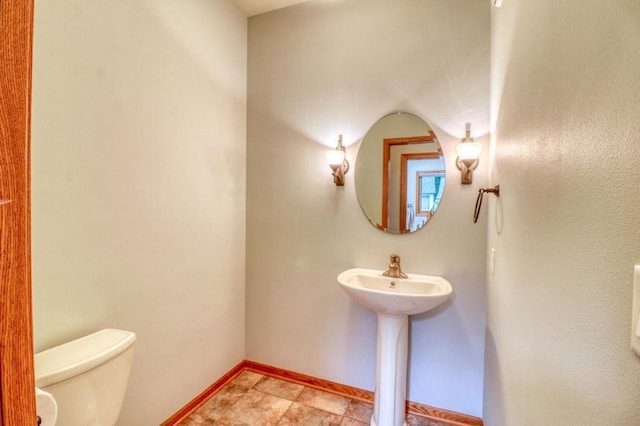 bathroom featuring baseboards and toilet