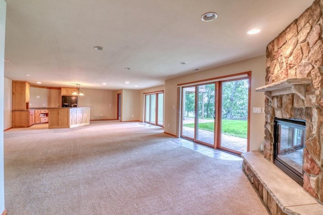 unfurnished living room with a notable chandelier, light colored carpet, a fireplace, recessed lighting, and baseboards
