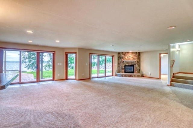 unfurnished living room featuring recessed lighting, baseboards, a stone fireplace, and carpet