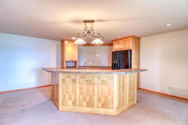kitchen with light brown cabinetry, baseboards, black fridge, and light colored carpet