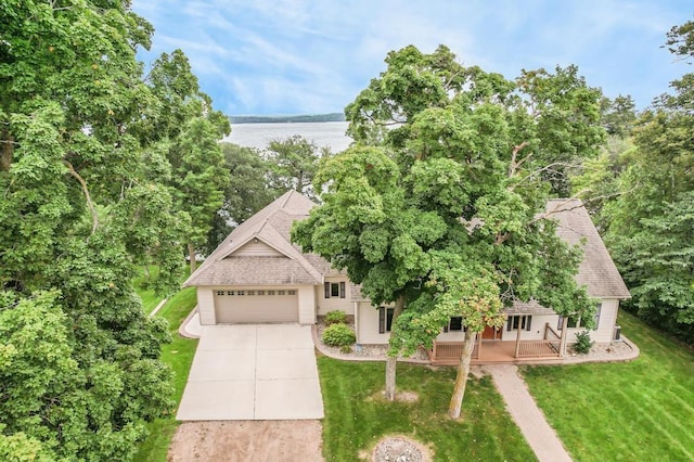 view of front of house with a front yard, a shingled roof, an attached garage, a water view, and driveway