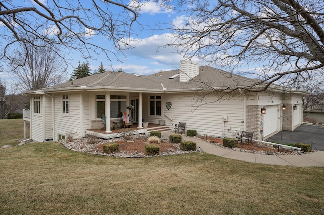 back of property with a garage, aphalt driveway, a lawn, a chimney, and roof with shingles