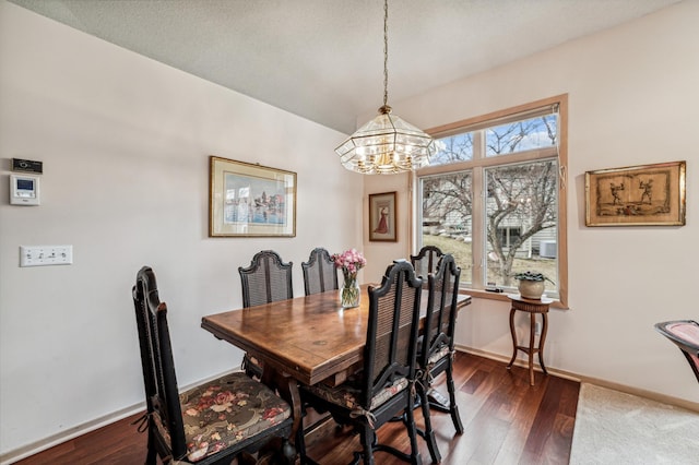 dining area with baseboards, a notable chandelier, and wood finished floors