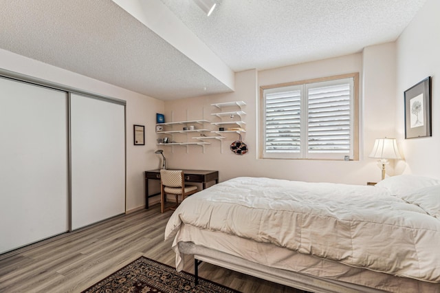 bedroom with a closet, wood finished floors, and a textured ceiling