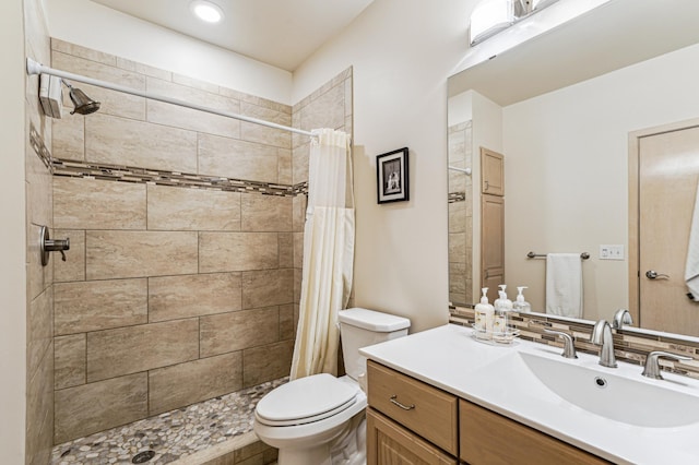 bathroom featuring toilet, a tile shower, and vanity