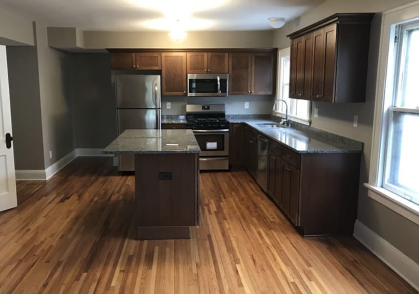 kitchen with stainless steel appliances, a wealth of natural light, a kitchen island, a sink, and dark wood-style floors