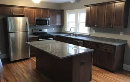 kitchen with a sink, appliances with stainless steel finishes, dark brown cabinets, a kitchen island, and light wood finished floors