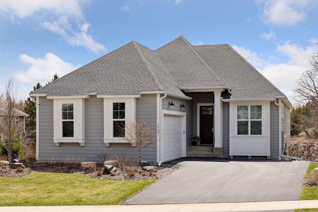 ranch-style home featuring an attached garage, a shingled roof, driveway, and a front lawn