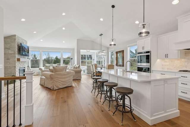 kitchen featuring stainless steel double oven, open floor plan, a sink, and plenty of natural light