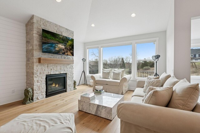 living room with high vaulted ceiling, wood finished floors, a stone fireplace, and recessed lighting