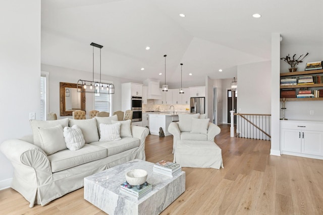 living room featuring lofted ceiling, a chandelier, recessed lighting, and light wood-style floors