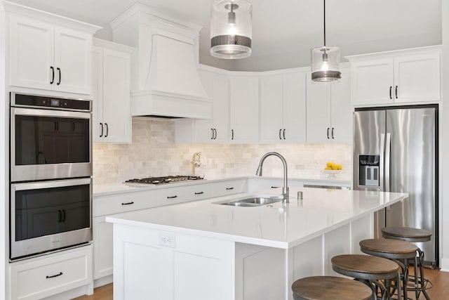 kitchen featuring a sink, a breakfast bar, stainless steel appliances, light wood-style flooring, and premium range hood