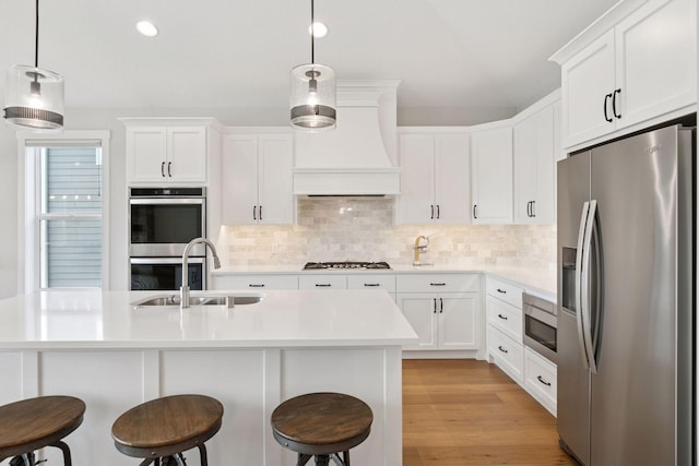 kitchen featuring a kitchen breakfast bar, a sink, light countertops, backsplash, and appliances with stainless steel finishes