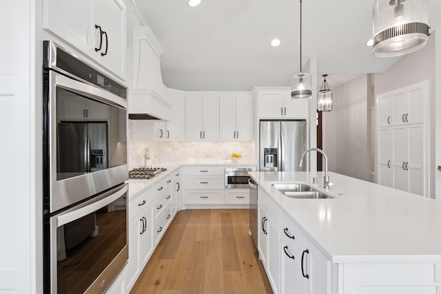 kitchen with light countertops, a kitchen island with sink, appliances with stainless steel finishes, and a sink